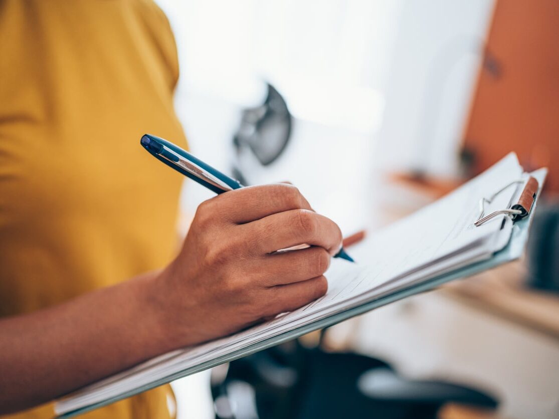 Woman hand writing on clipboard with a pen.